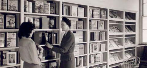 black and white photo of librarians in front of bookshelves